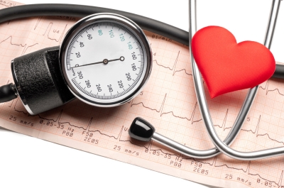 A blood pressure cuff and inflatable heart positioned over top of a printed blood pressure reading.