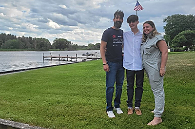 three people standing in front of a lake; Chad Williams, his son, and his wife