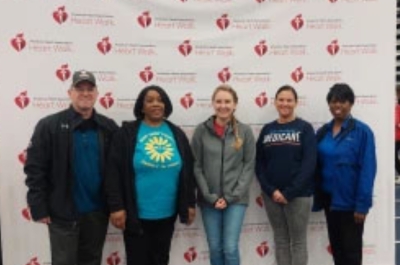 Five people, including Sherry, smiling in front of an American Heart Association banner.