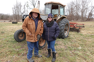 Dj and Heather standing in front of a tractor
