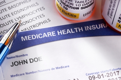 Sample Medicare card on a medical document with a pen and pill bottles nearby.