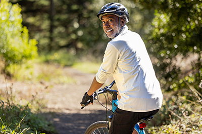 older man riding a bicycle on wooded path